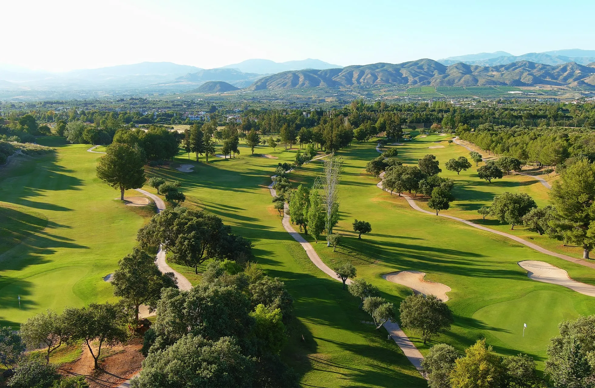 Aerial view of Lauro Golf's fairways and oaks with the sierra behind