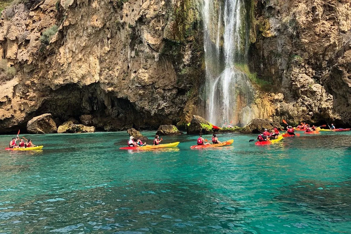 Kayakers paddling towards a waterfall on the Maro cliffs near Nerja