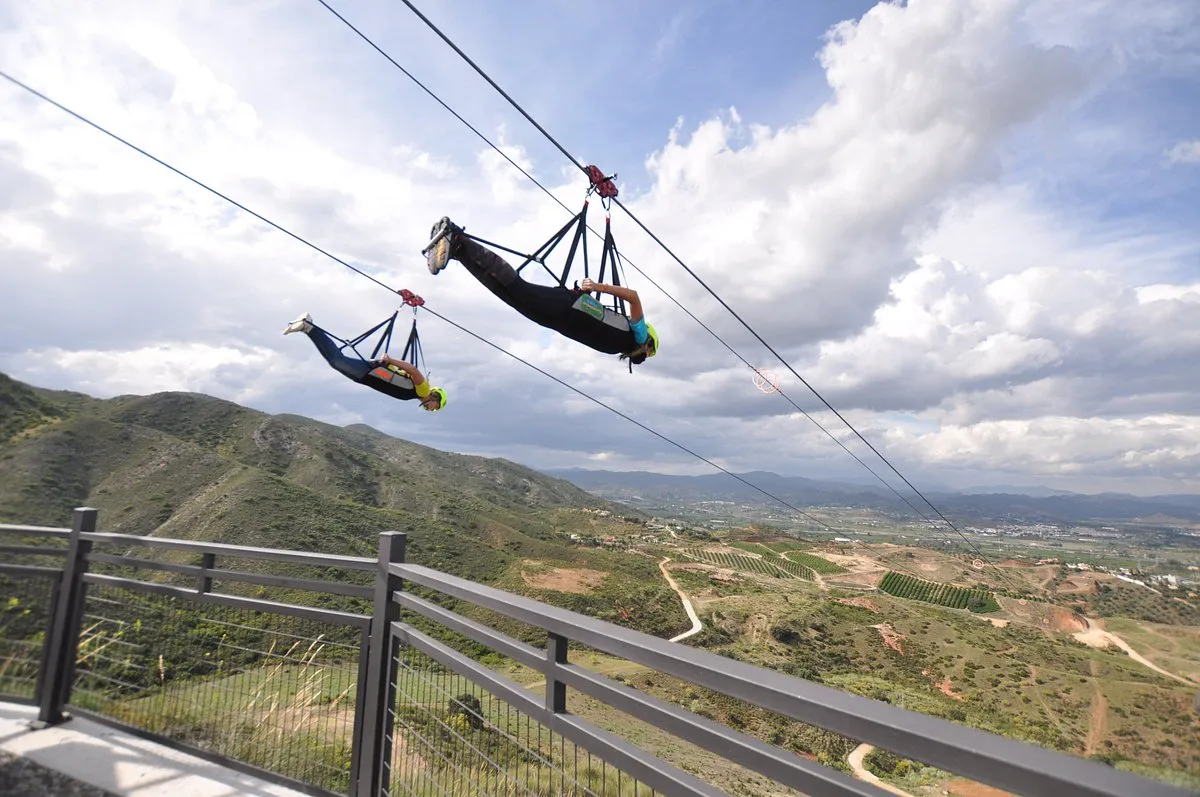 Two people flying head-first on the Sunview Park zip line above the valley
