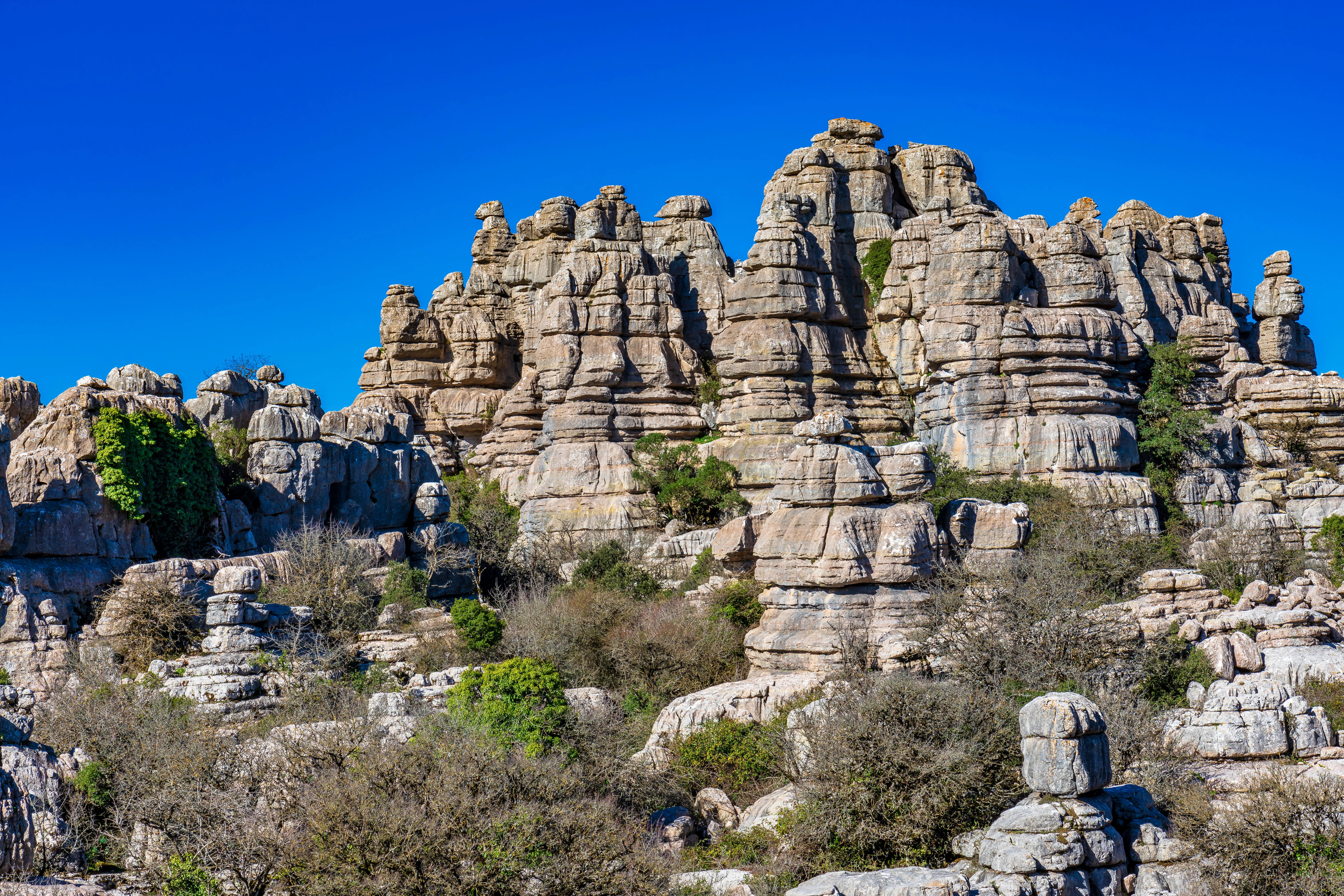 Weathered grey limestone rock towers under a blue sky at El Torcal de Antequera